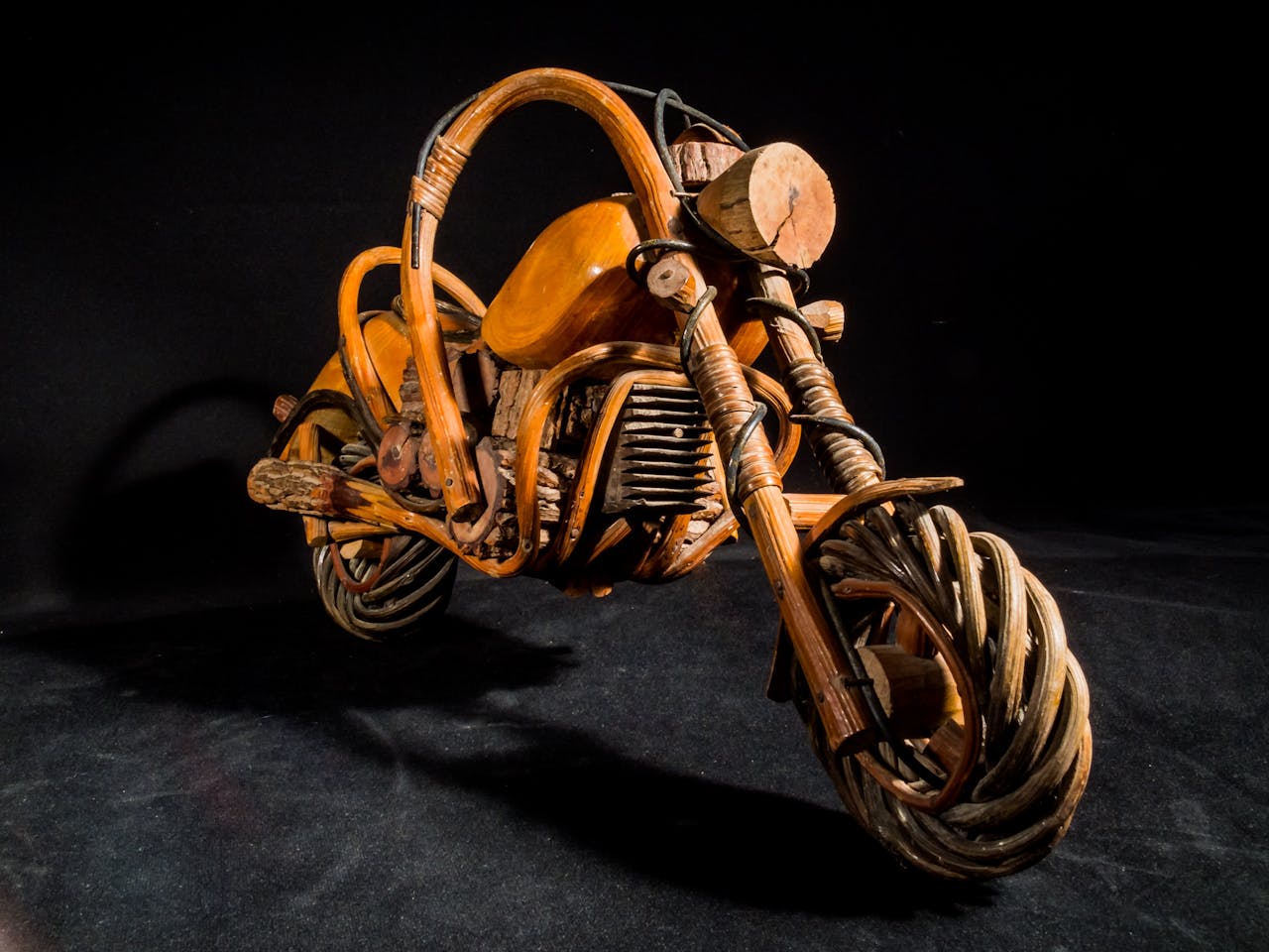 services-02 Intricate handcrafted wooden motorcycle sculpture on a dark background.